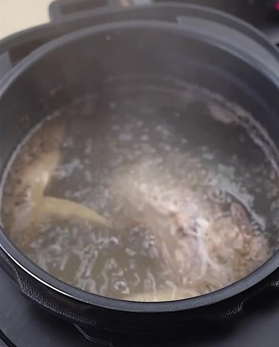 Huesos y patas de pollo enjuagados en un tazón de acero inoxidable.