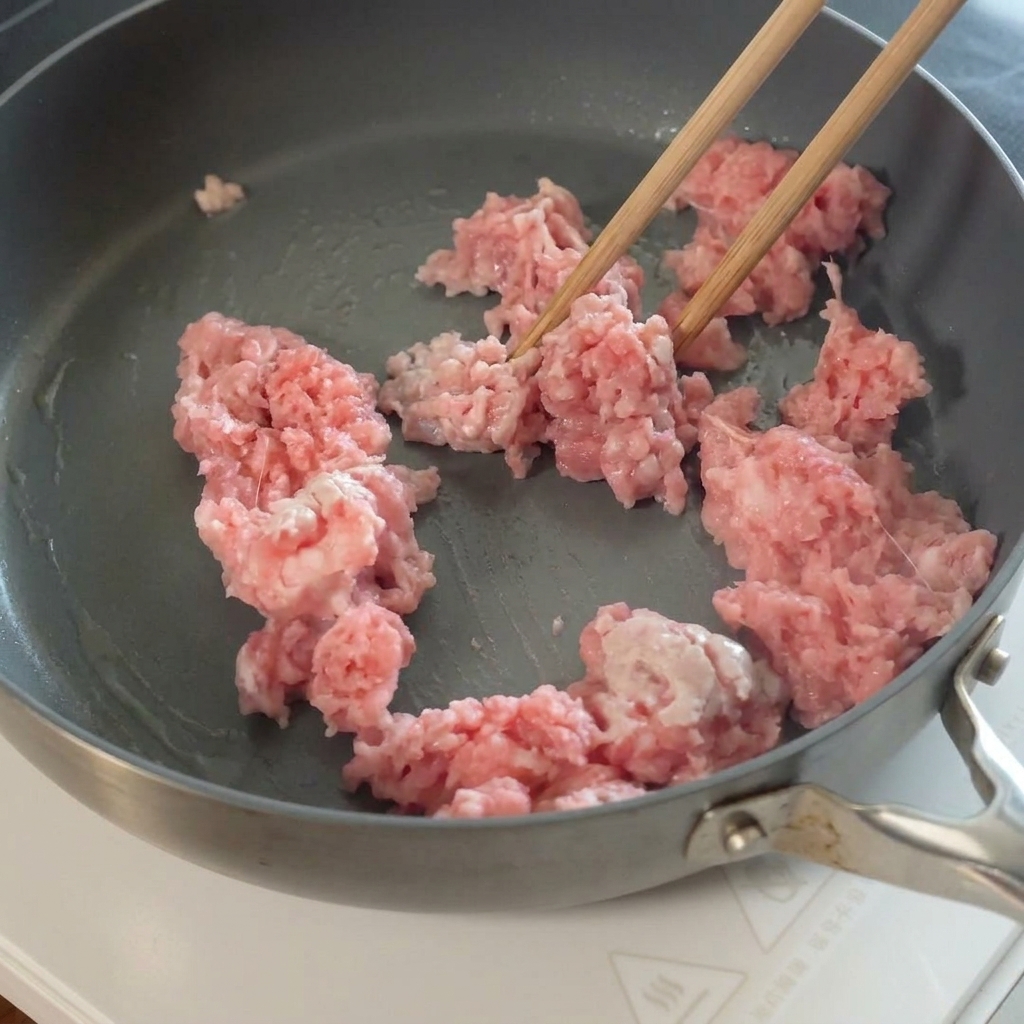 Ajo en rodajas siendo añadido a la carne picada cocinada en la sartén.