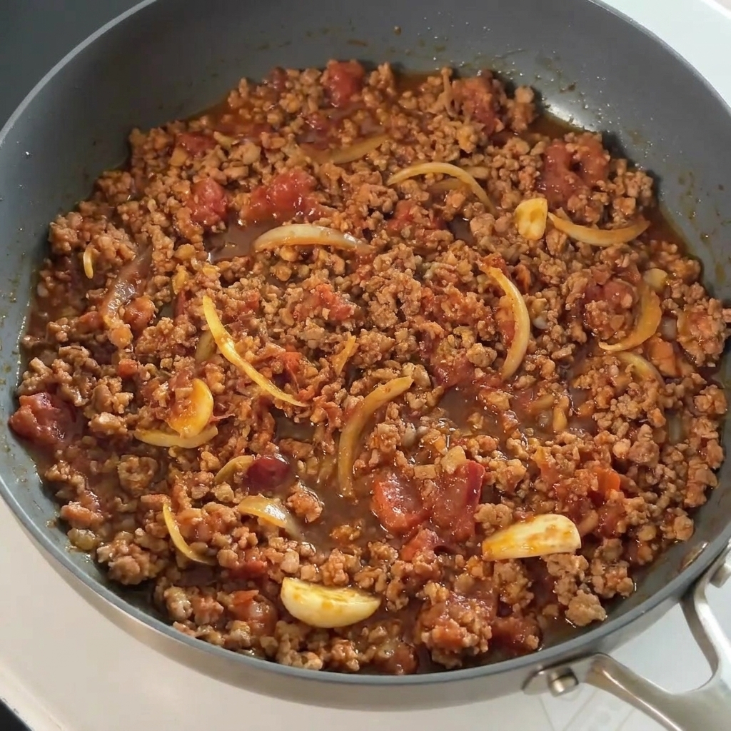 Salsa de soja vertiéndose sobre la carne sazonada en la sartén.