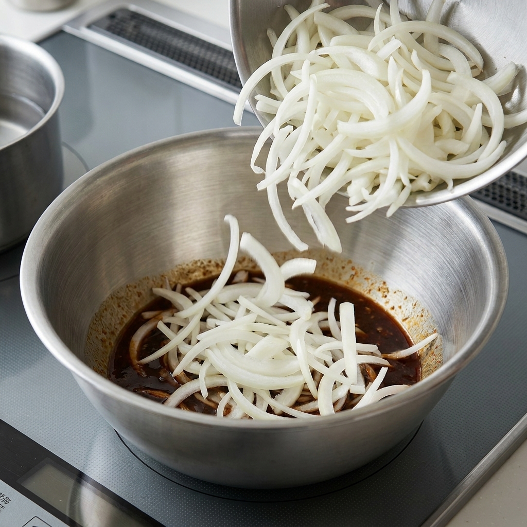 Fideos cocidos mezclándose con la salsa de sésamo en un tazón grande.
