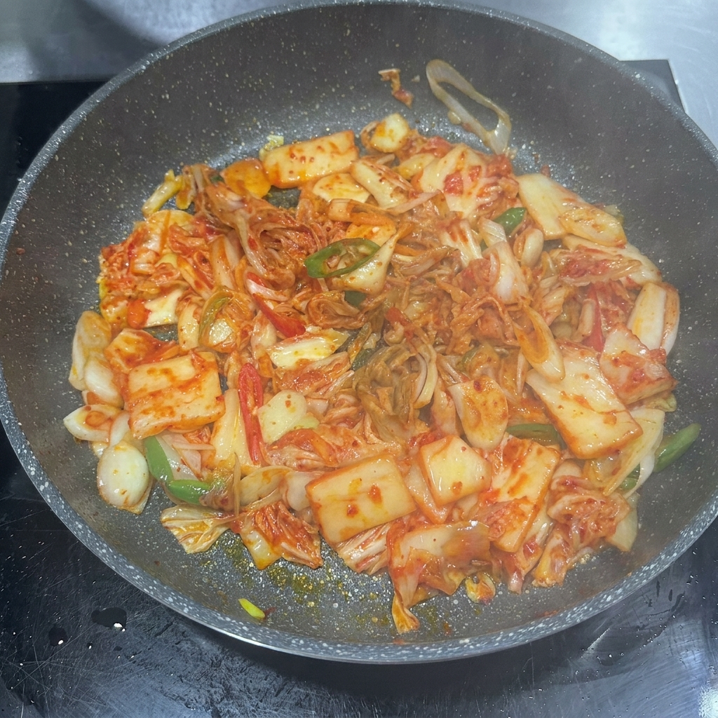 Pasta de chile, salsa de soja y azúcar siendo añadidos a la sartén con kimchi.