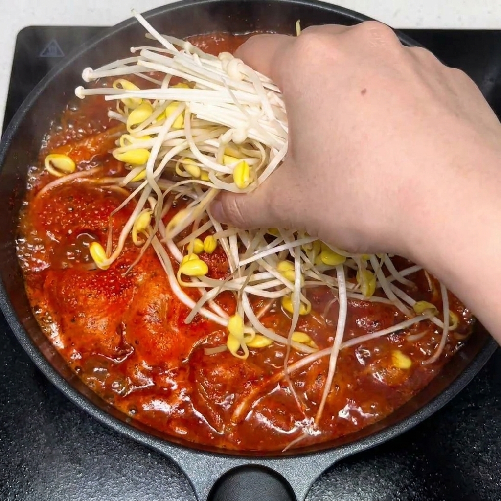 Ajo picado y especias mezclándose en la sopa roja y picante.