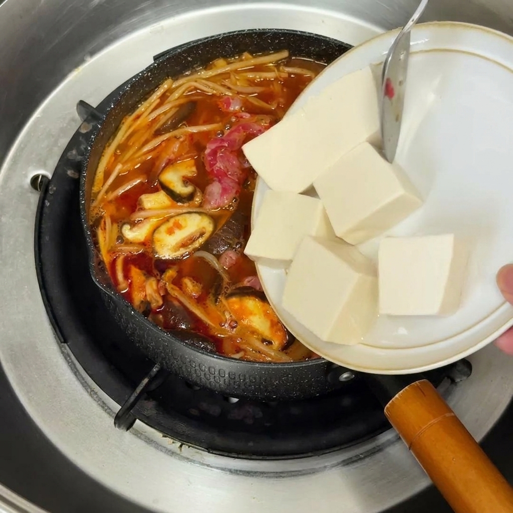 Cebolla roja picada salteándose en una sartén amarilla con aceite brillante.