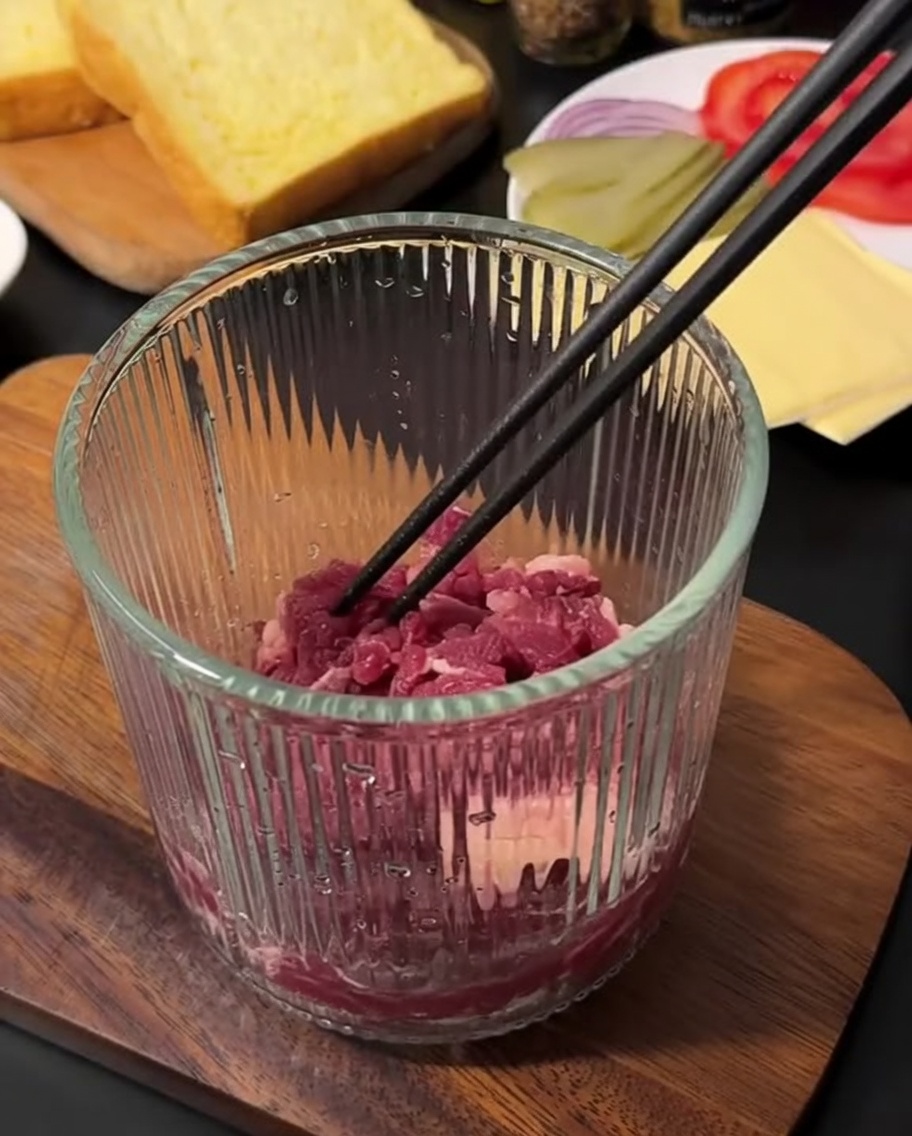 Carne molida cruda y fresca dentro de una picadora manual de alimentos.