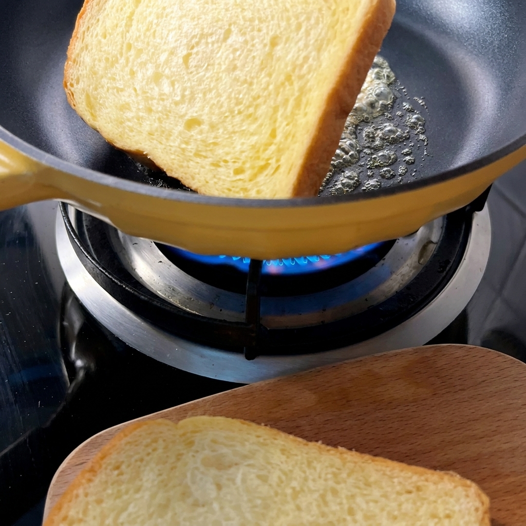 Rebanadas de pan tostadas doradas en una sartén amarilla con mantequilla derretida.