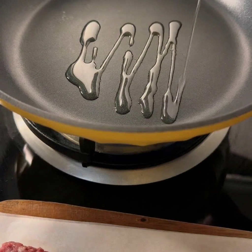 Dos hamburguesas de carne sazonadas sellándose en una sartén caliente con aceite visible.
