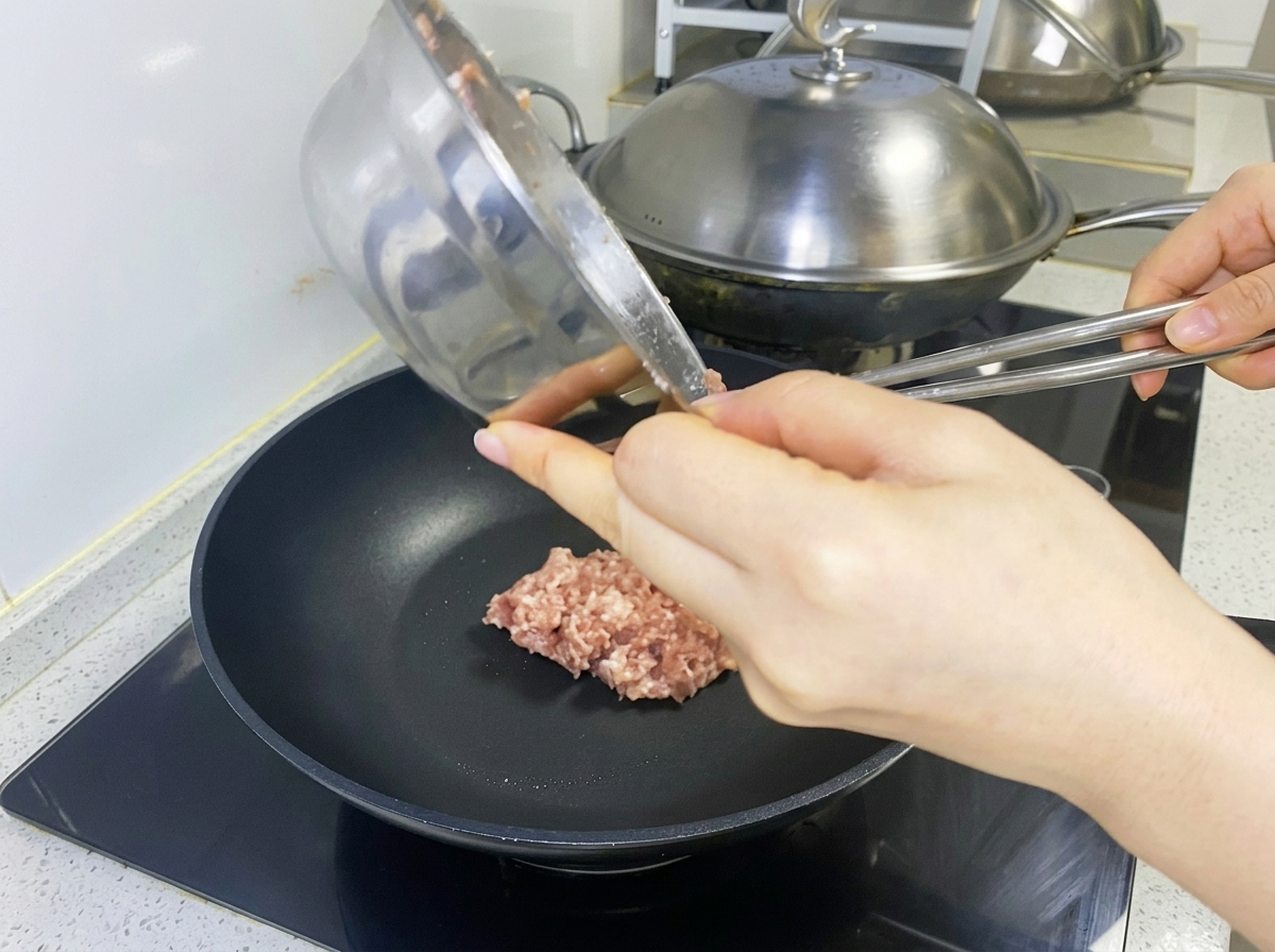 Mezcla de carne cruda siendo colocada en una sartén negra para formar la hamburguesa.