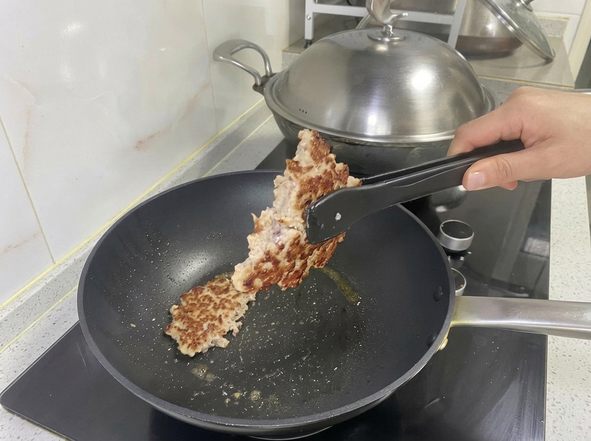 Hamburguesa de cerdo dorada siendo levantada de la sartén con pinzas.