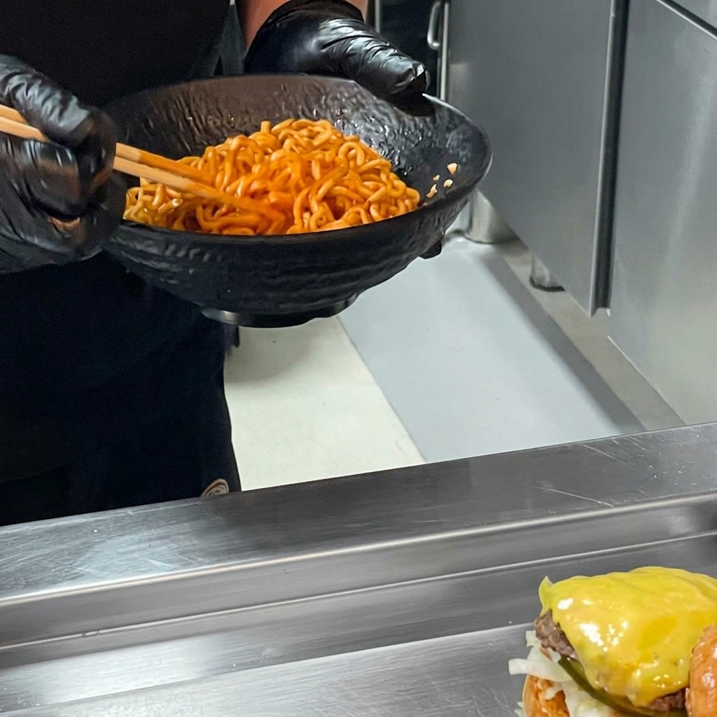Una hamburguesa de ramen de pollo picante terminada al añadir un gran montículo de fideos ramen sobre la carne y cubrirla con el pan superior.