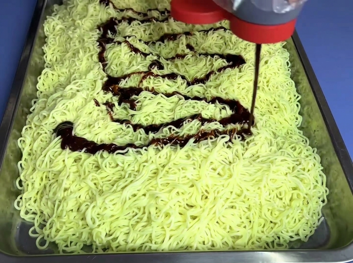 Salsa de fideos fire no picante siendo vertida desde una botella sobre una cama de fideos.