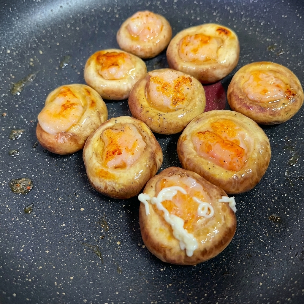 Primer plano del aderezo siendo exprimido sobre la superficie de los champiñones rellenos de camarón.