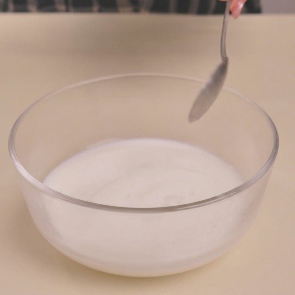 Leche cortada en un tazón de vidrio después de añadir vinagre, creando una textura similar al suero de leche.
