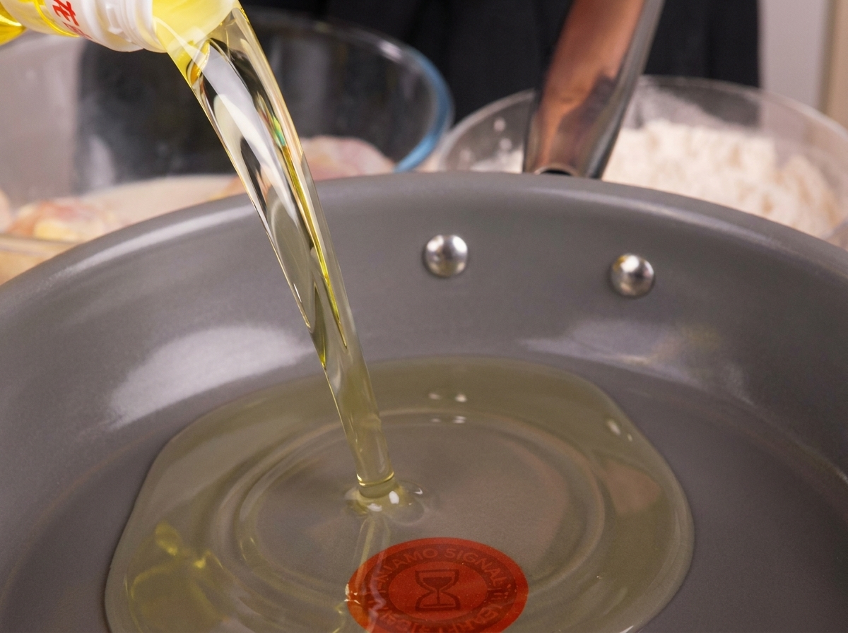 Aceite de cocina vertido en una sartén profunda, preparándose para ser calentado.