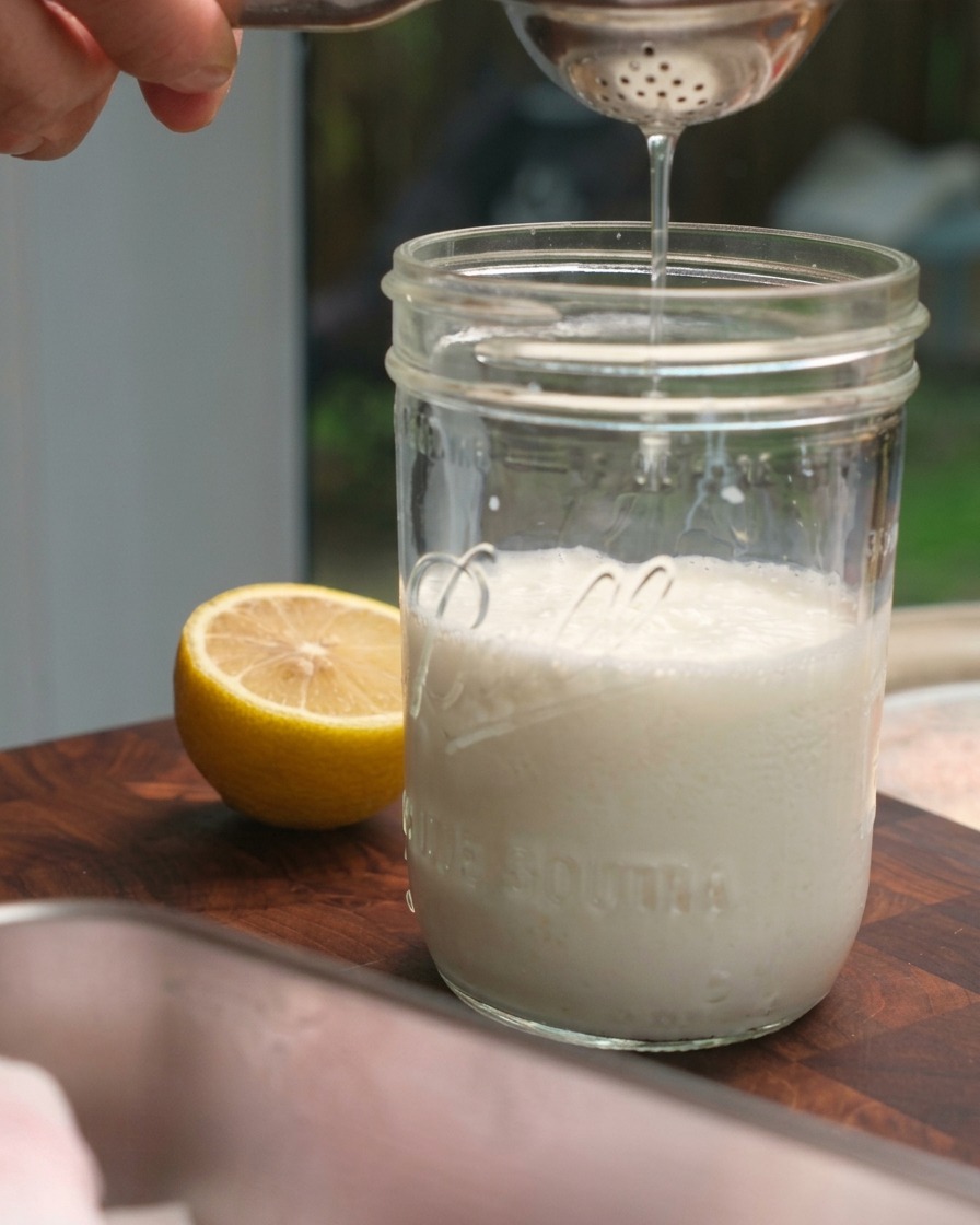 Jugo de limón fresco siendo exprimido en un frasco de vidrio con leche.