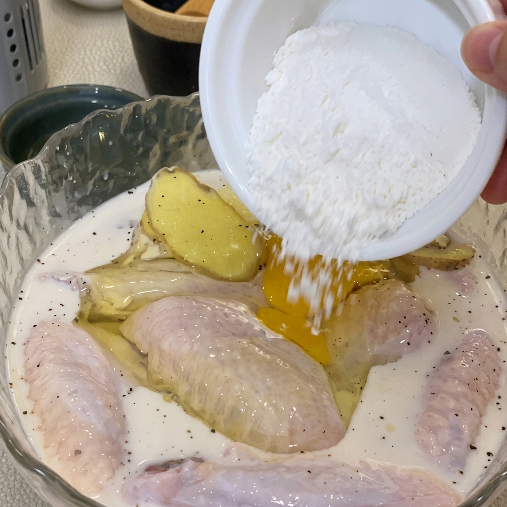 Mano mezclando un huevo y harina en el bol con el pollo para crear una masa.
