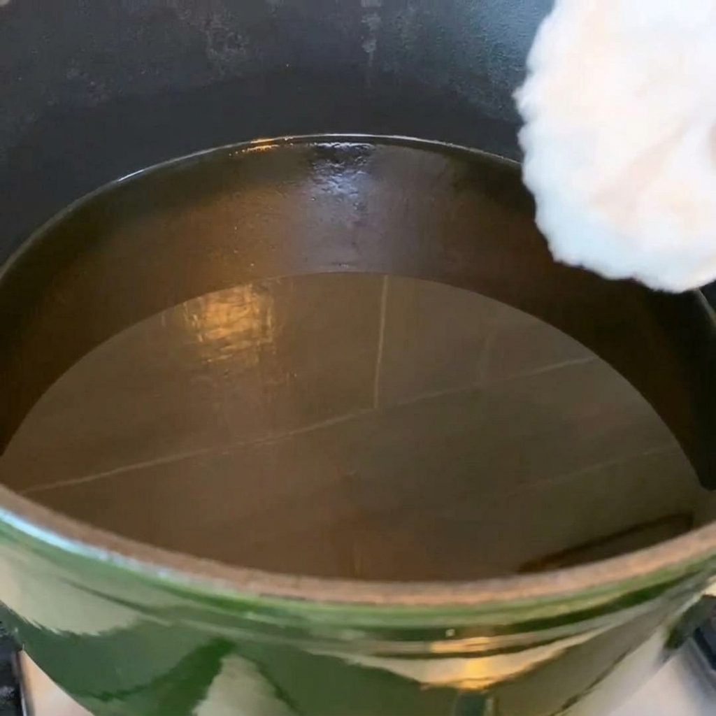 Alitas de pollo friéndose en una sartén con aceite caliente, mostrando un color dorado.
