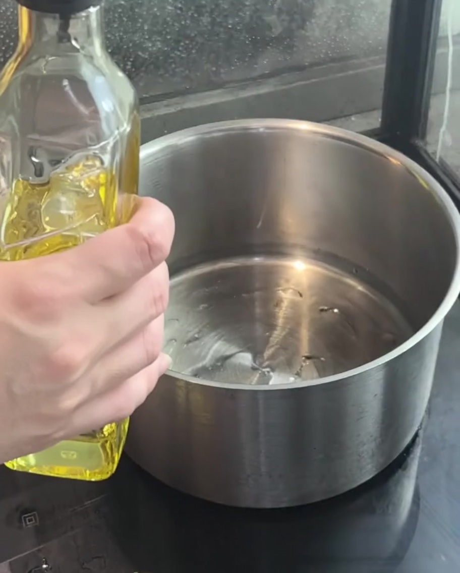 Cebolla morada picada sofriéndose en aceite caliente dentro de una olla.