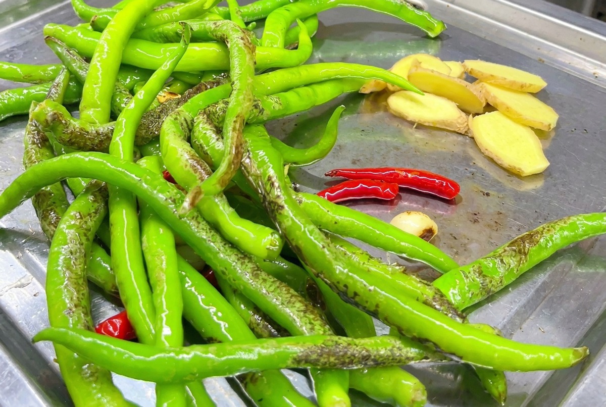 Rodajas de jengibre siendo selladas en la plancha con los chiles.