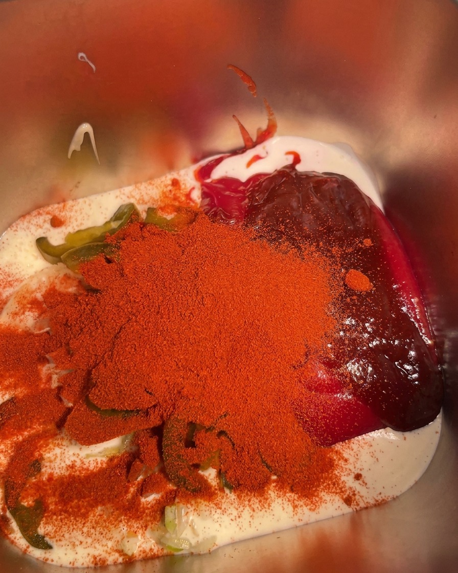 Ajo en polvo siendo espolvoreado sobre los ingredientes combinados en el recipiente de metal.