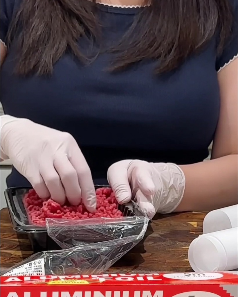Condimentando los filetes de carne picada cruda en una tabla de madera con sal y pimienta.