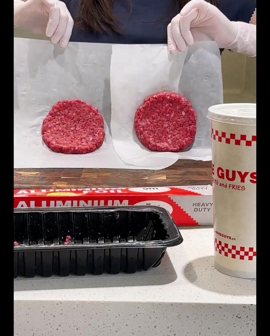 Dando la vuelta a la hamburguesa en la sartén con una espátula.