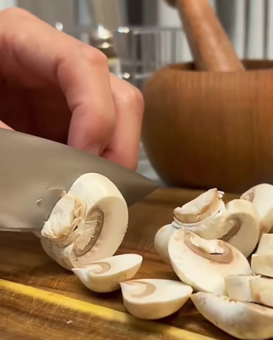 Champiñones frescos siendo cortados en láminas con un cuchillo.