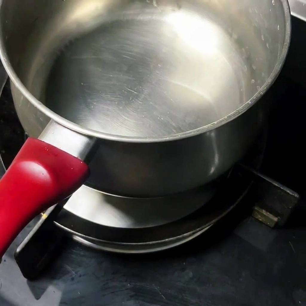 Un huevo crudo friéndose en una olla de acero inoxidable limpia sobre la cocina.