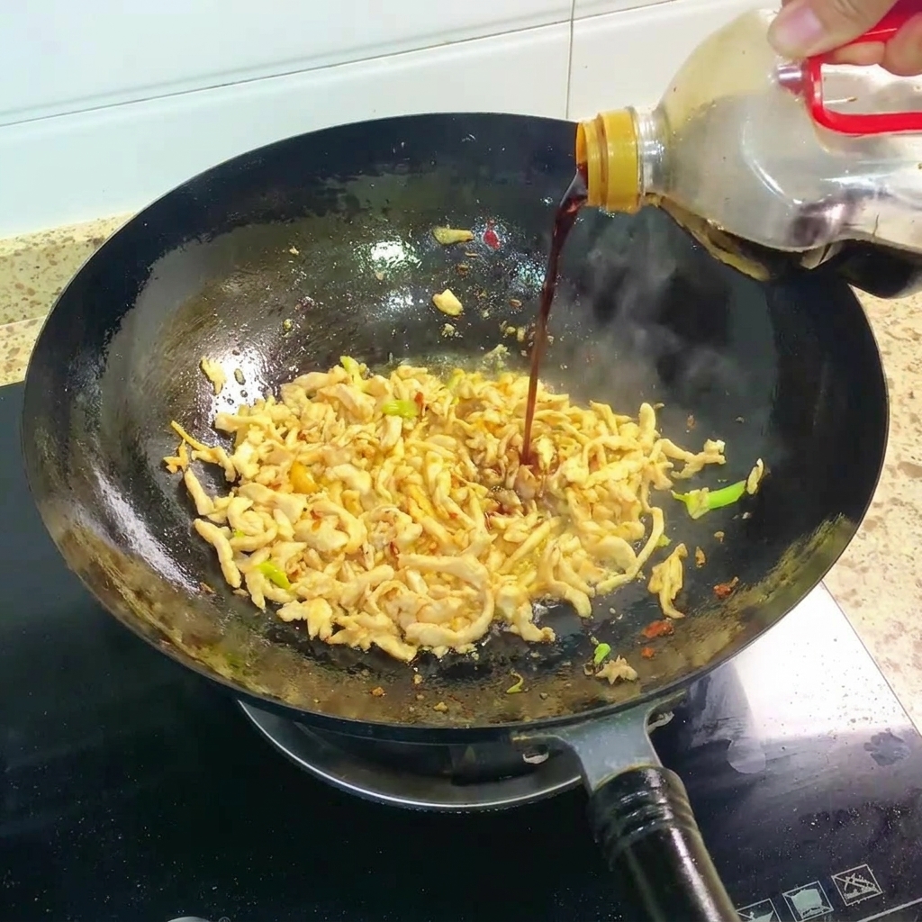 Salsa de soja oscura siendo vertida en el wok con el pollo salteado.