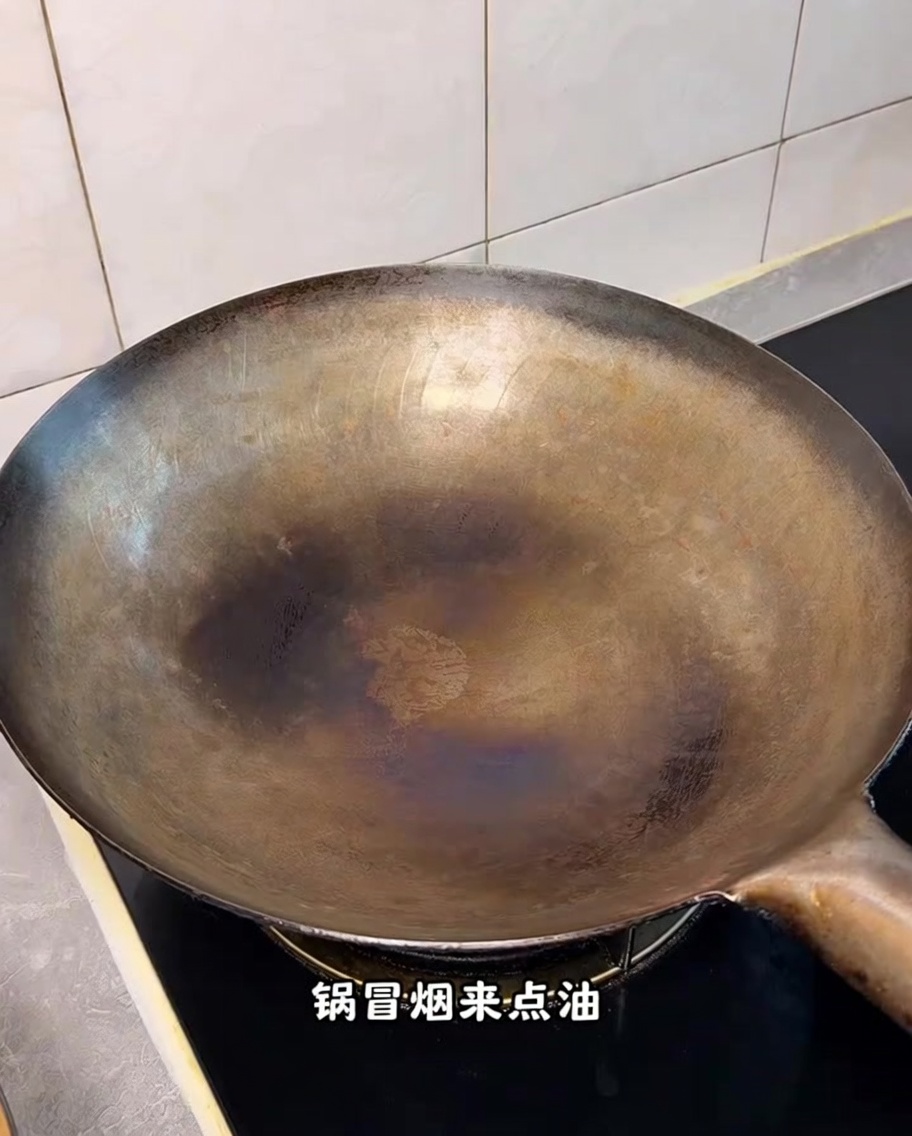 Un wok caliente y curado sobre la estufa con volutas de humo visible.