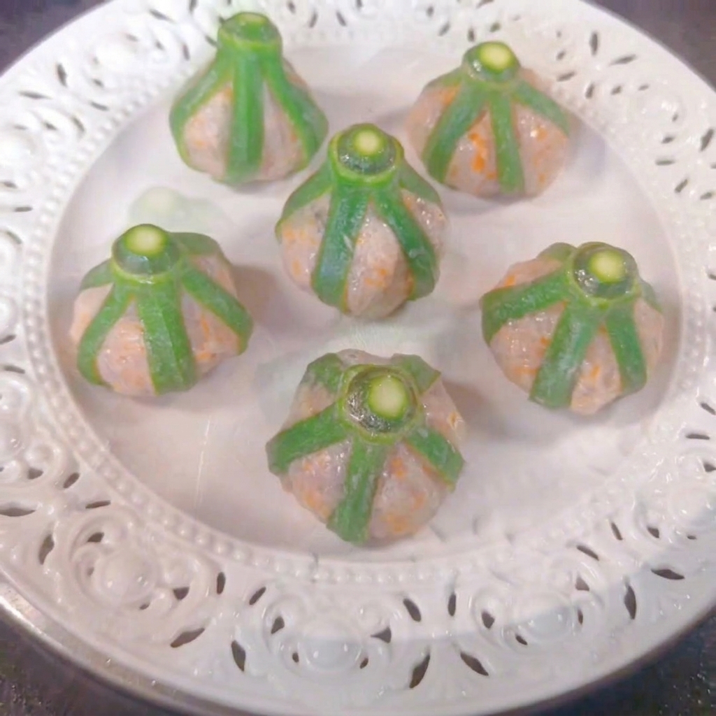 Seis bocados de okra y camarón dispuestos en un plato blanco dentro de una vaporera.