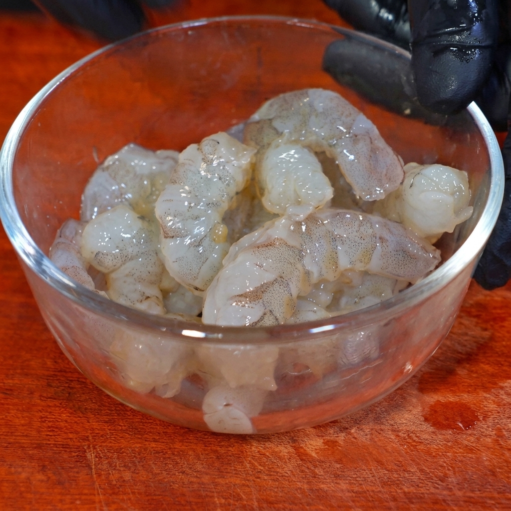 Gambas marinándose en un bol de cristal con condimentos y almidón de maíz.