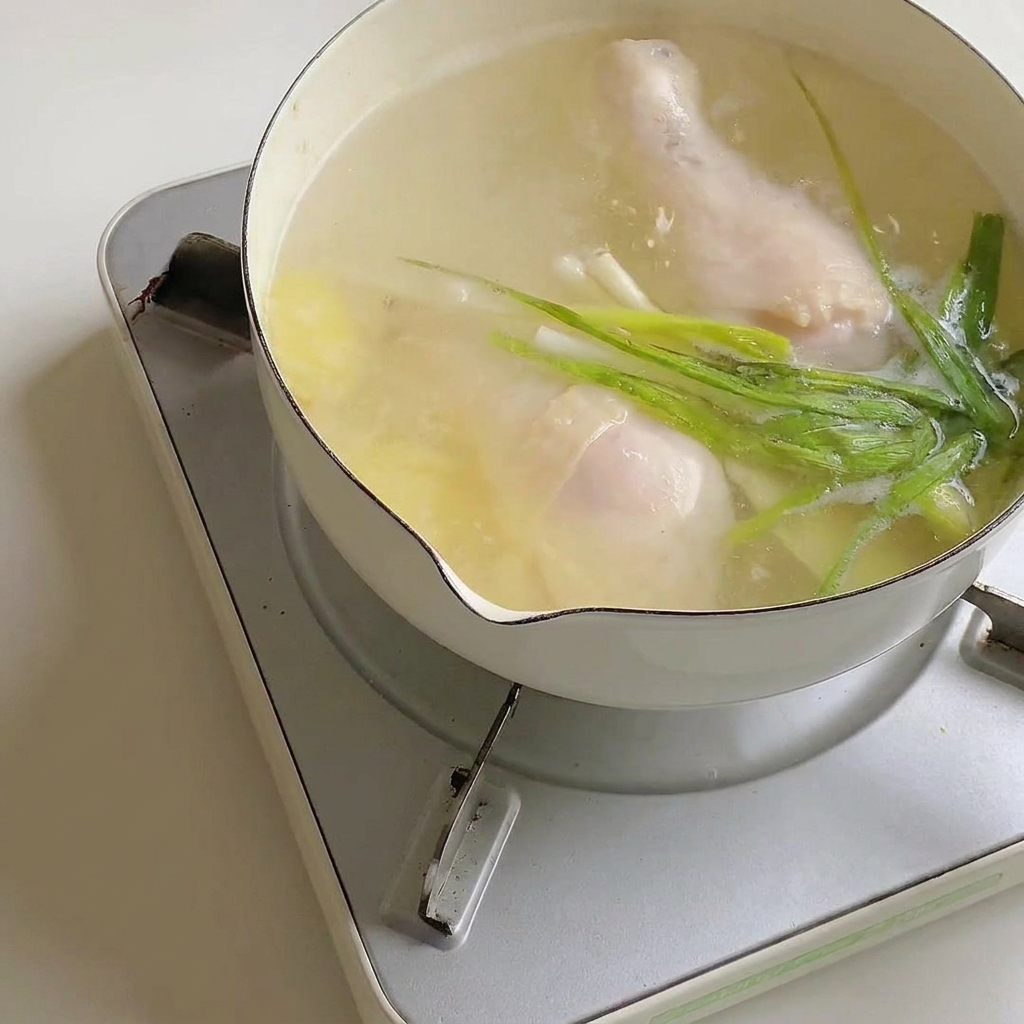 Polvo de condimento para ramen mezclándose en la olla de caldo con pollo.