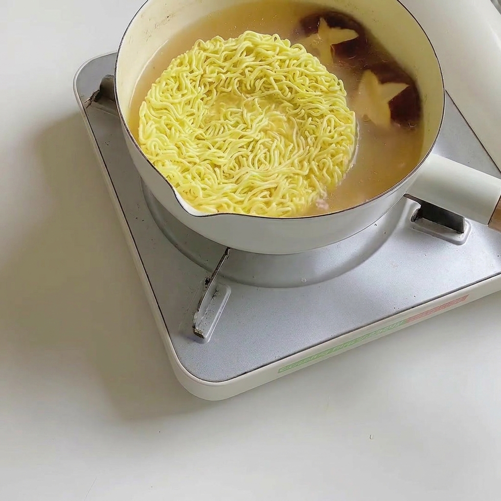 Hojas frescas de bok choy añadiéndose a la olla de ramen.