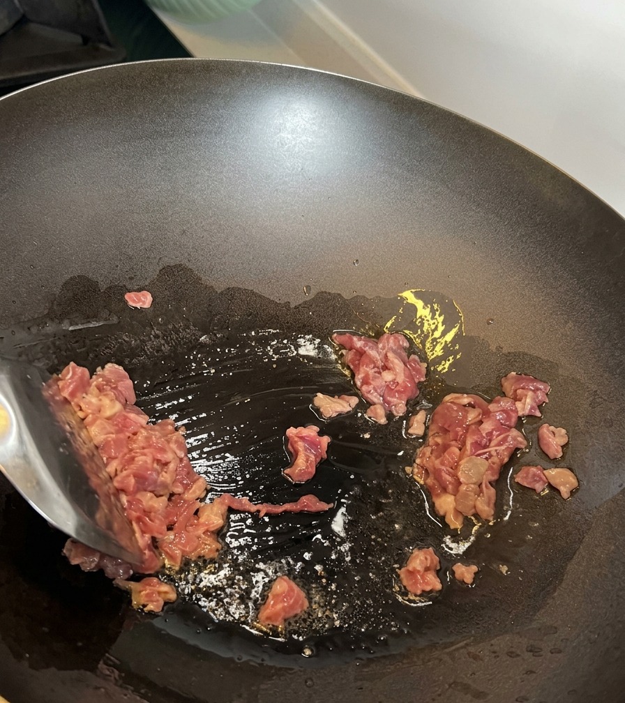 Trozos de ternera siendo salteados en un wok caliente.