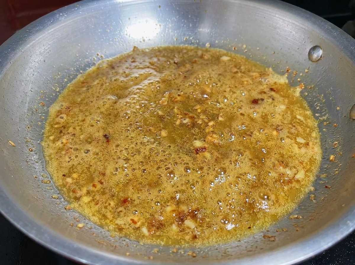 Ajo picado y camarones cocinándose juntos en una base de aceite de oliva infusionado.