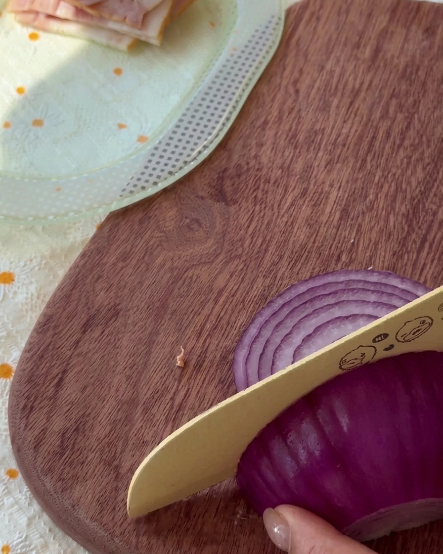 Cebolla morada cortada en tiras finas sobre una tabla de madera.