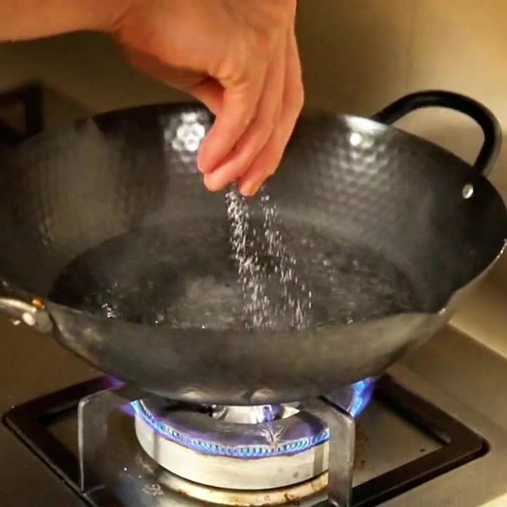 Una mano espolvoreando sal en una olla grande con agua hirviendo en la estufa.