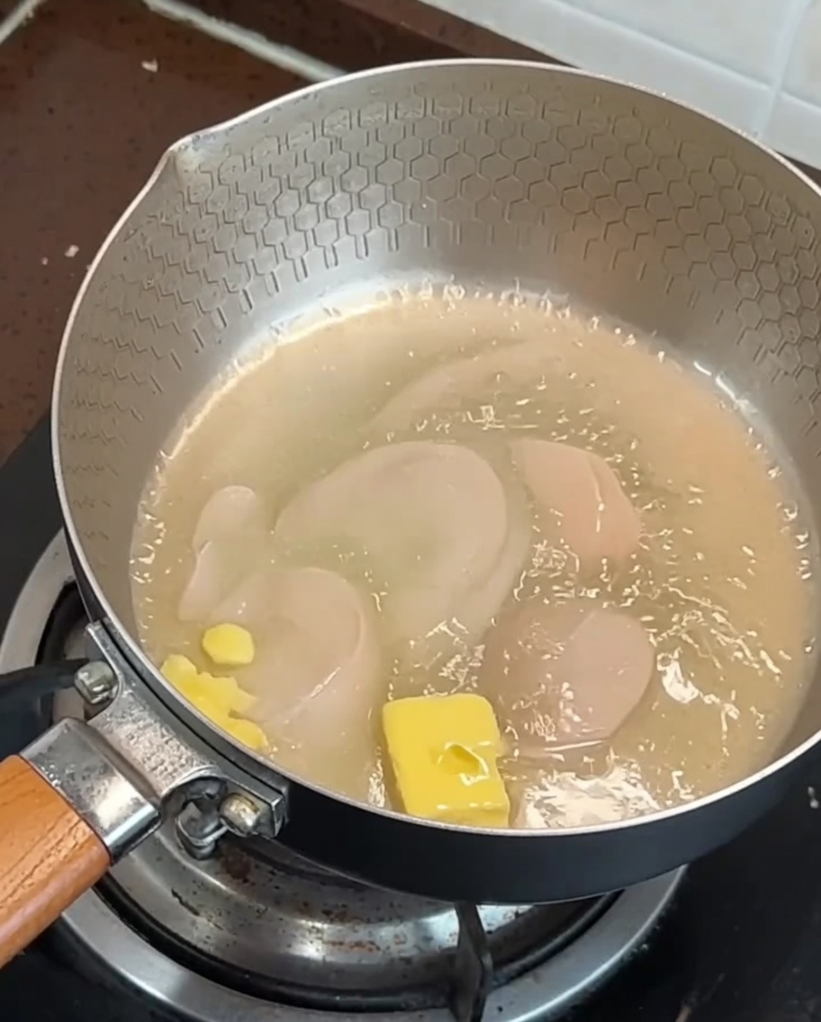 Tiras de beicon y ajo friéndose en una sartén con mantequilla derretida.