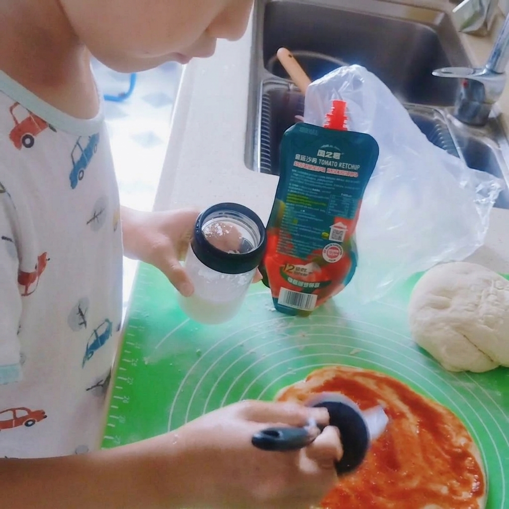 Sal siendo espolvoreada sobre la salsa de tomate en la base de la pizza.