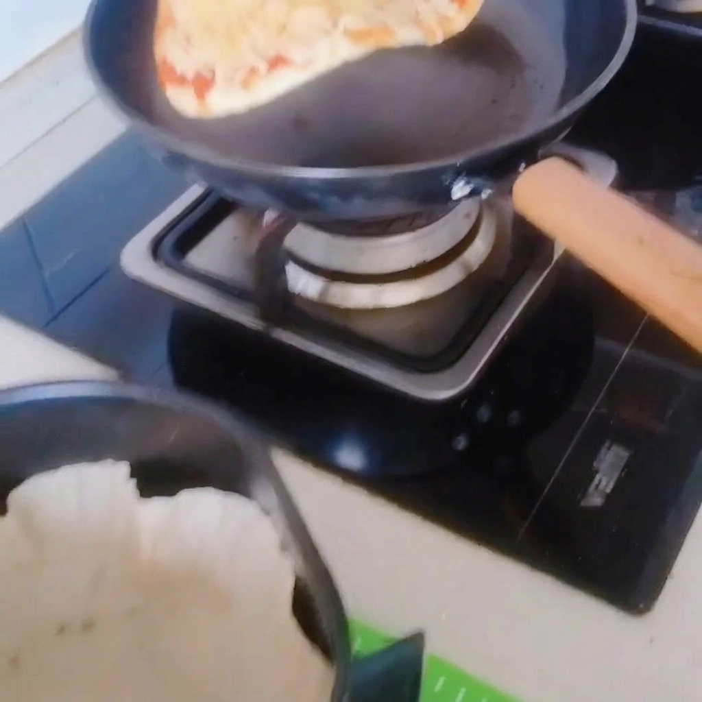 La pizza siendo movida con cuidado desde la sartén a la cesta de la freidora con papel de horno.