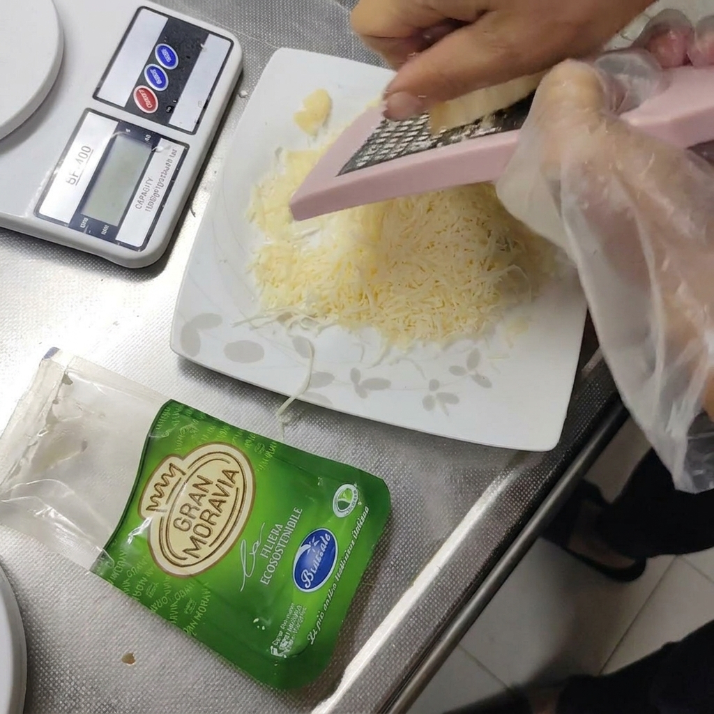 Queso duro Gran Moravia siendo rallado en un plato pequeño.