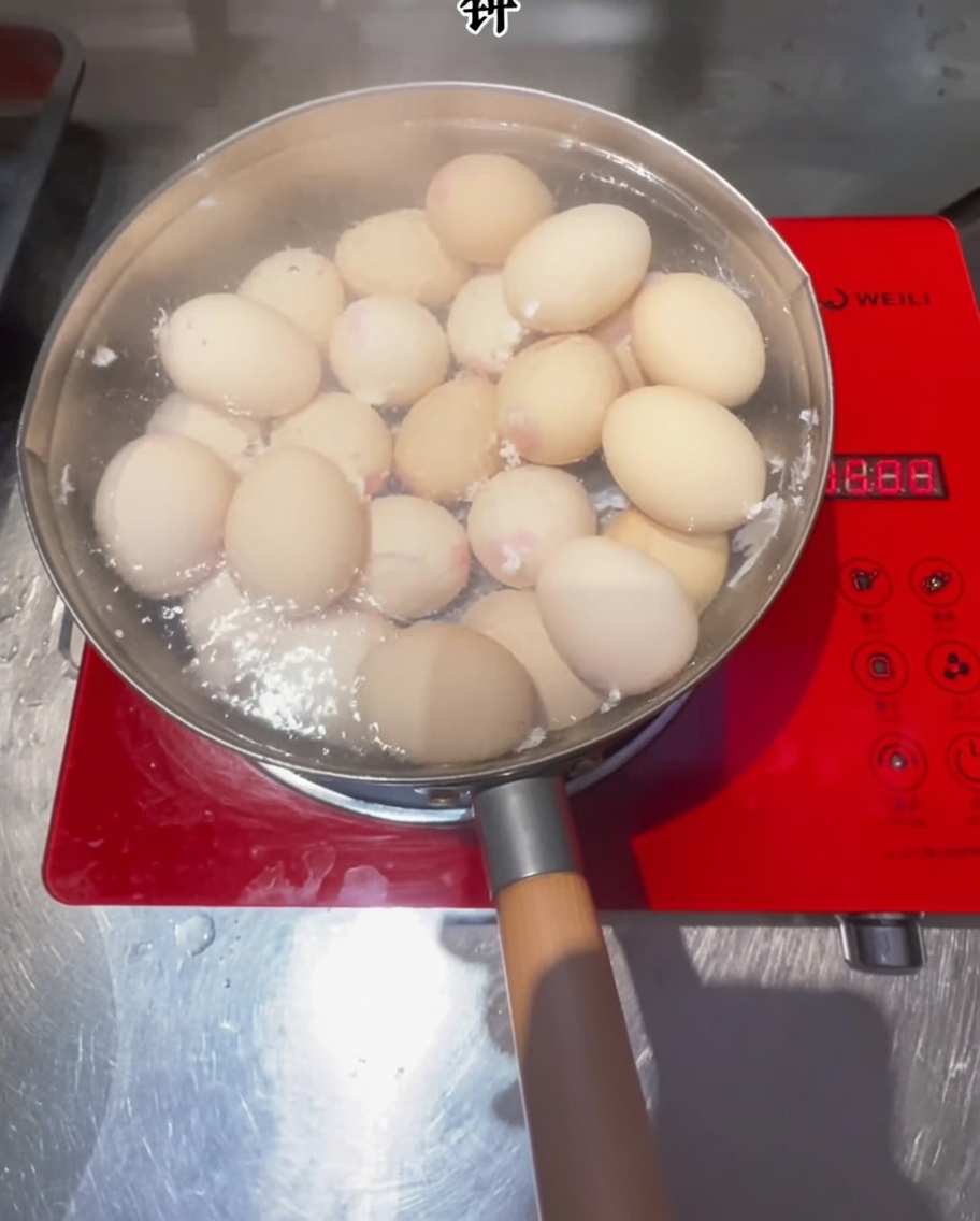 Huevos cocinándose en una olla con agua hirviendo sobre una estufa de inducción.