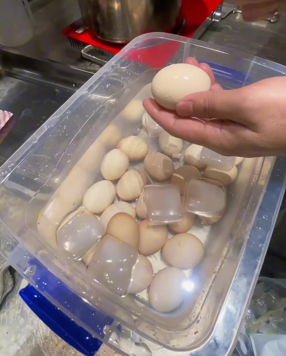 Retirando las cáscaras de huevos cocidos enfriados usando una cuchara de metal.