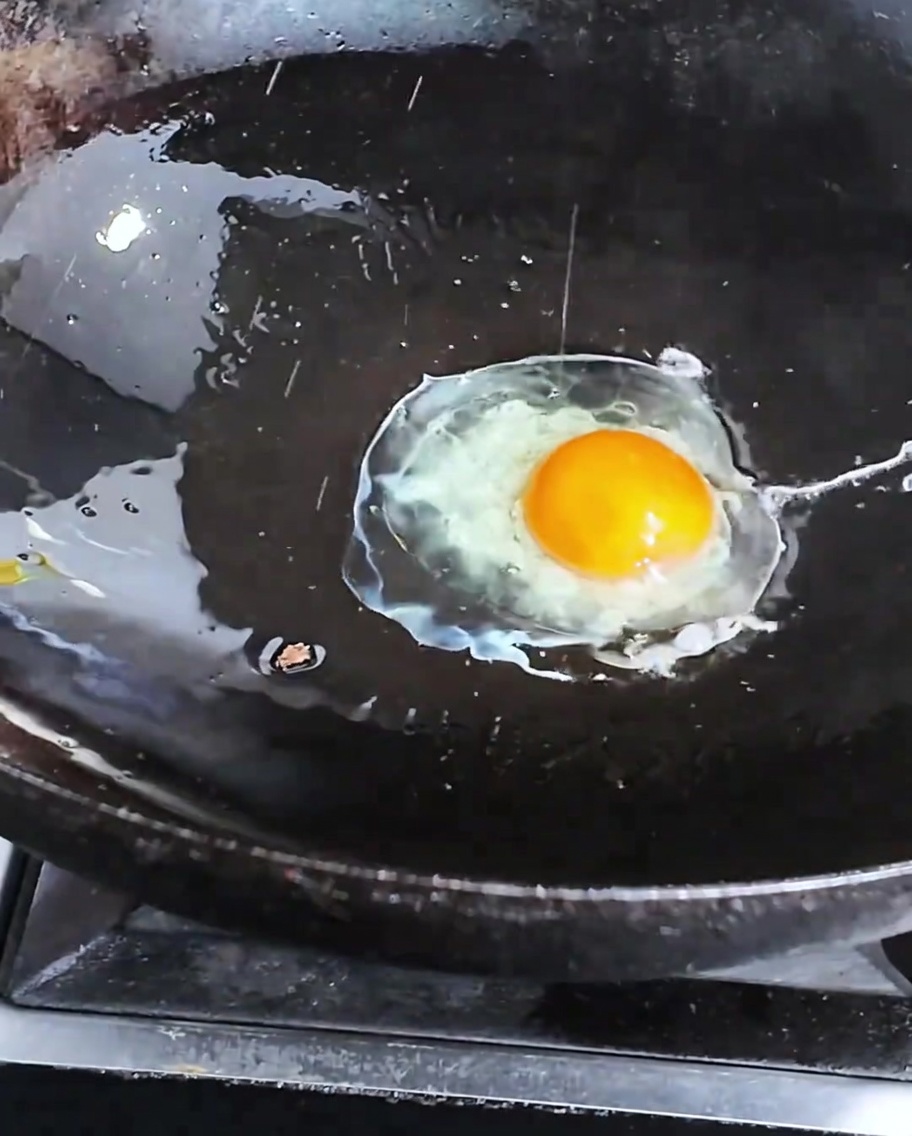 Un huevo friéndose en un wok caliente.