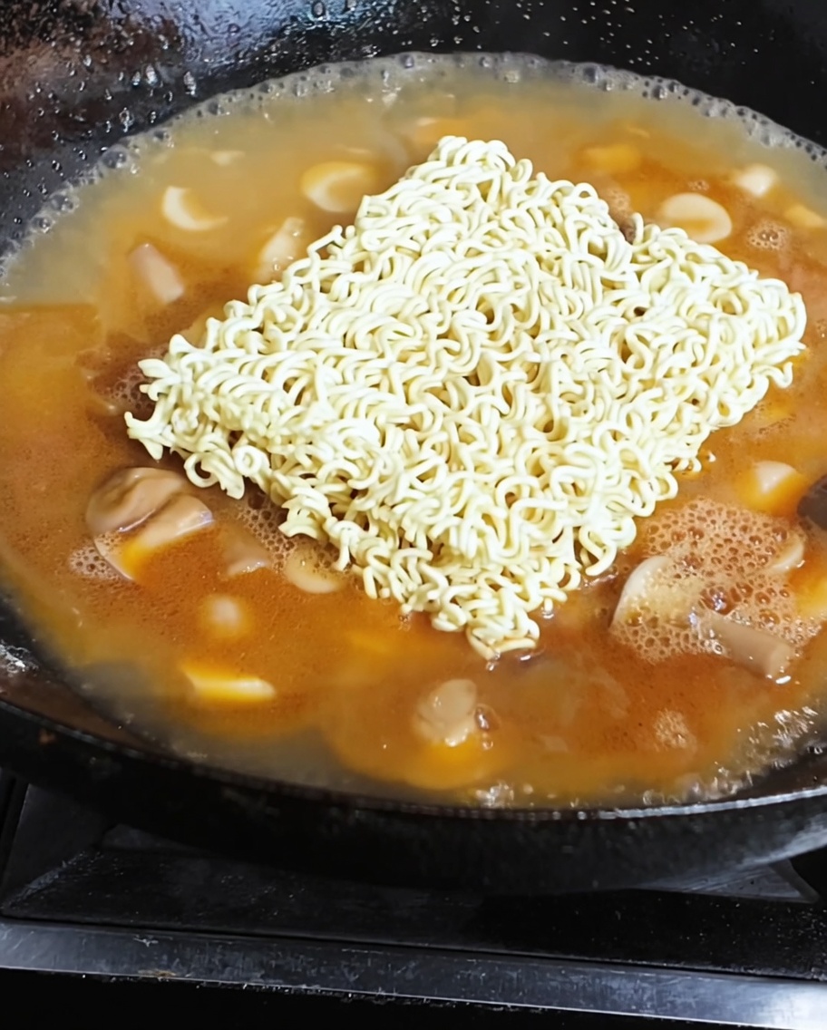 Fideos instantáneos y un huevo frito hirviendo a fuego lento en un caldo rico y sabroso.