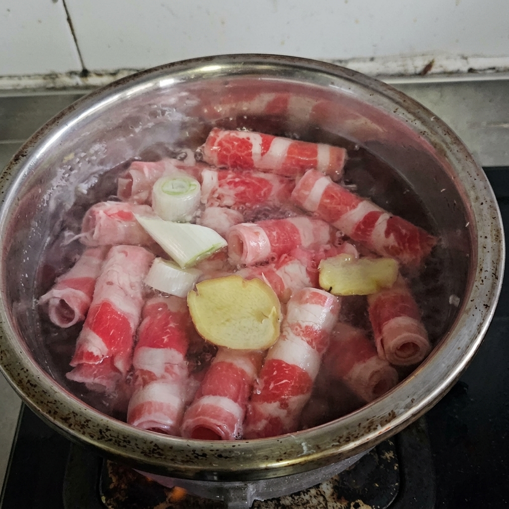 Rollos de carne hirviendo en una olla con aromáticos y vino de cocina.