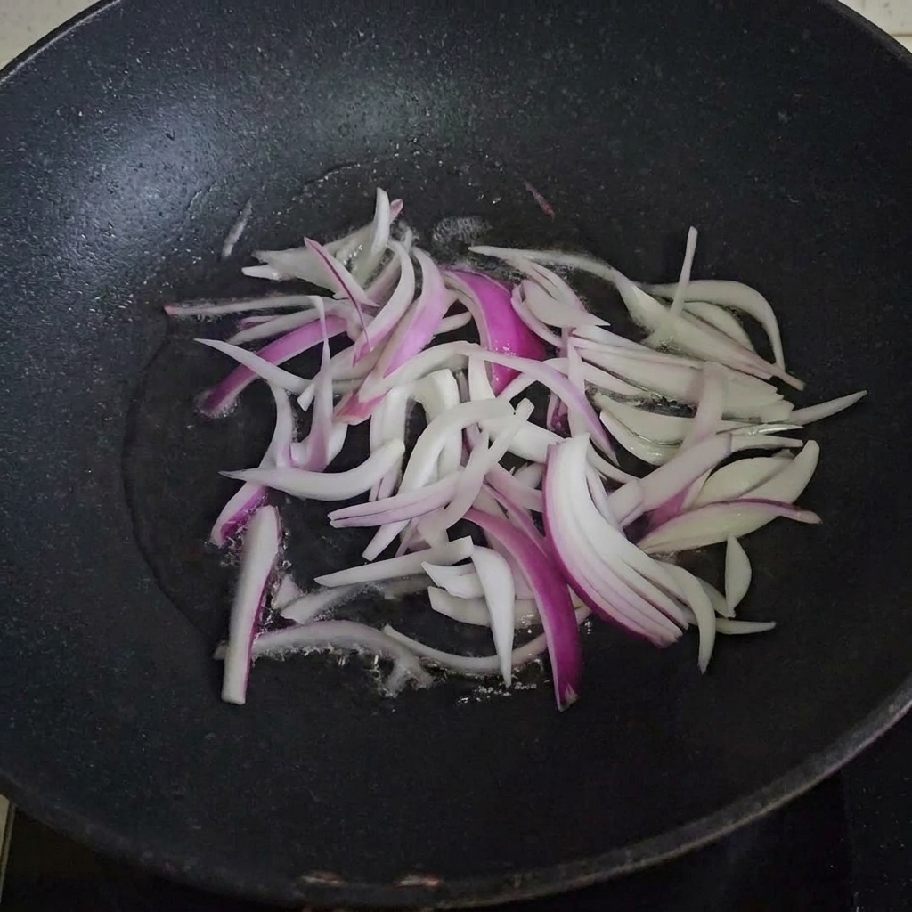 Rodajas de cebolla cocinándose en una sartén caliente con aceite.