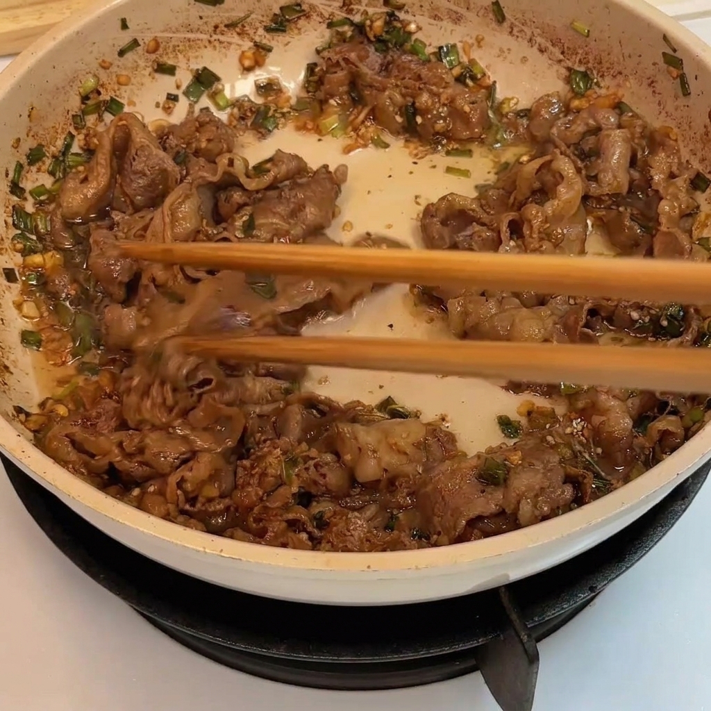 Láminas de ternera siendo salteadas en una sartén hasta quedar doradas y bien cocidas.