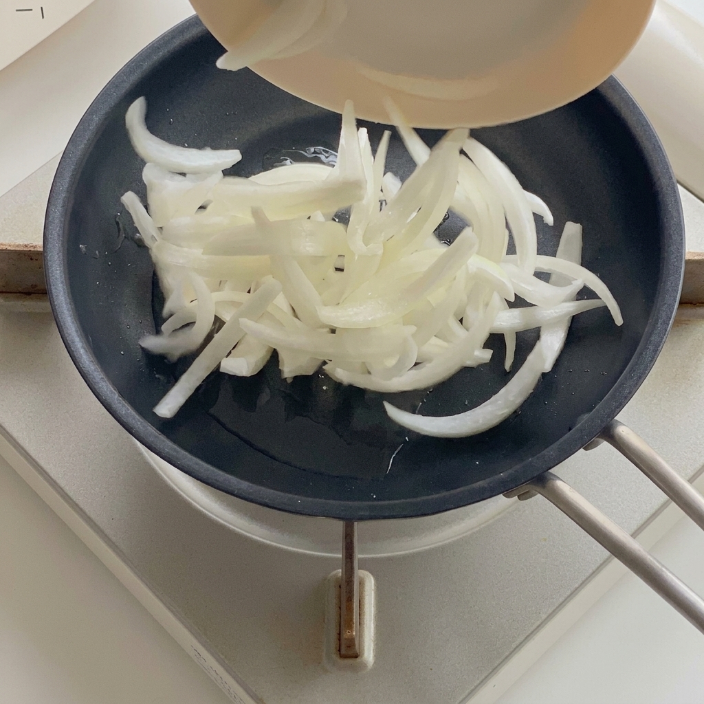 Cebollas suavizándose en una sartén con aceite caliente.