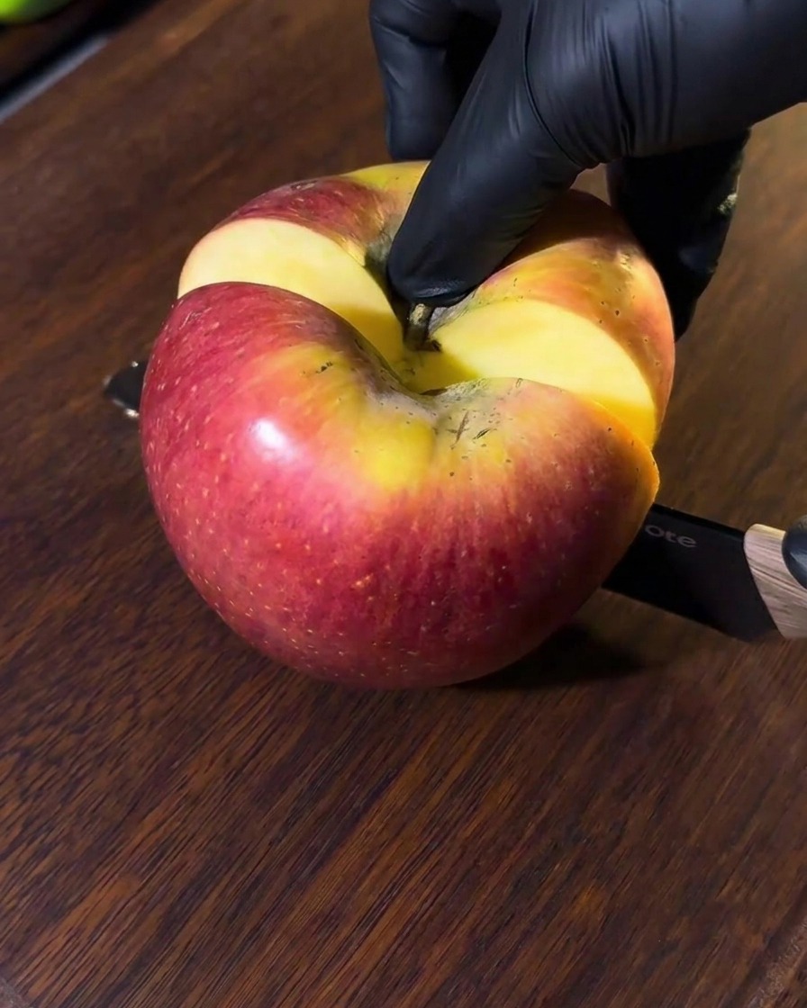 Una manzana siendo cortada en una tabla de madera, con trozos listos para la batidora.